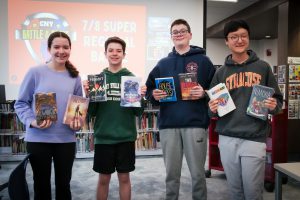 Wellwood Battle of the Books team holding books in the library after the SuperRegional battle