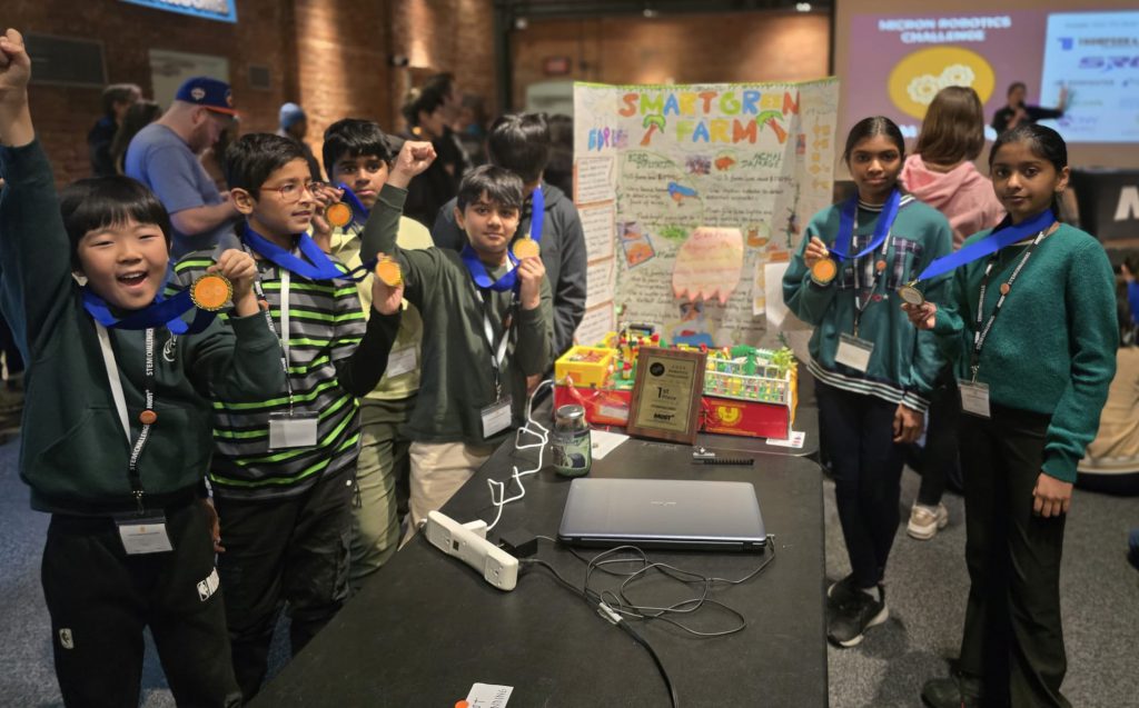 Several middle school students display their medals together at a robotics competition.