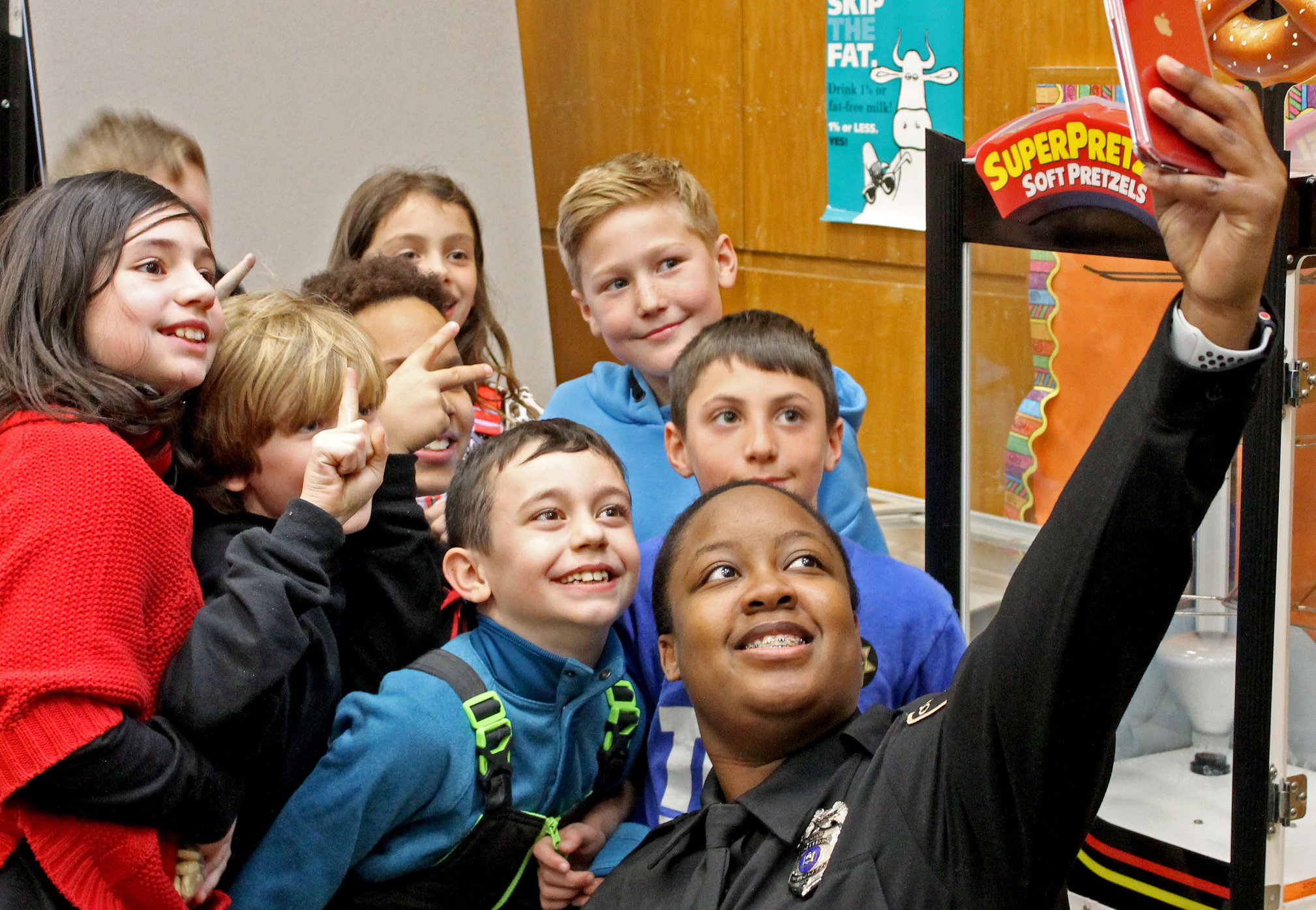 A school resource officer takes a selfie with several elementary students.