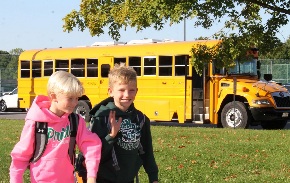 Two happy elementary students walk away from their school bus.