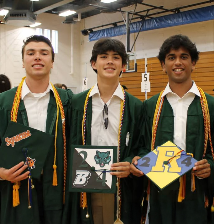 Three graduates display their caps which indicate the universities they will attend.