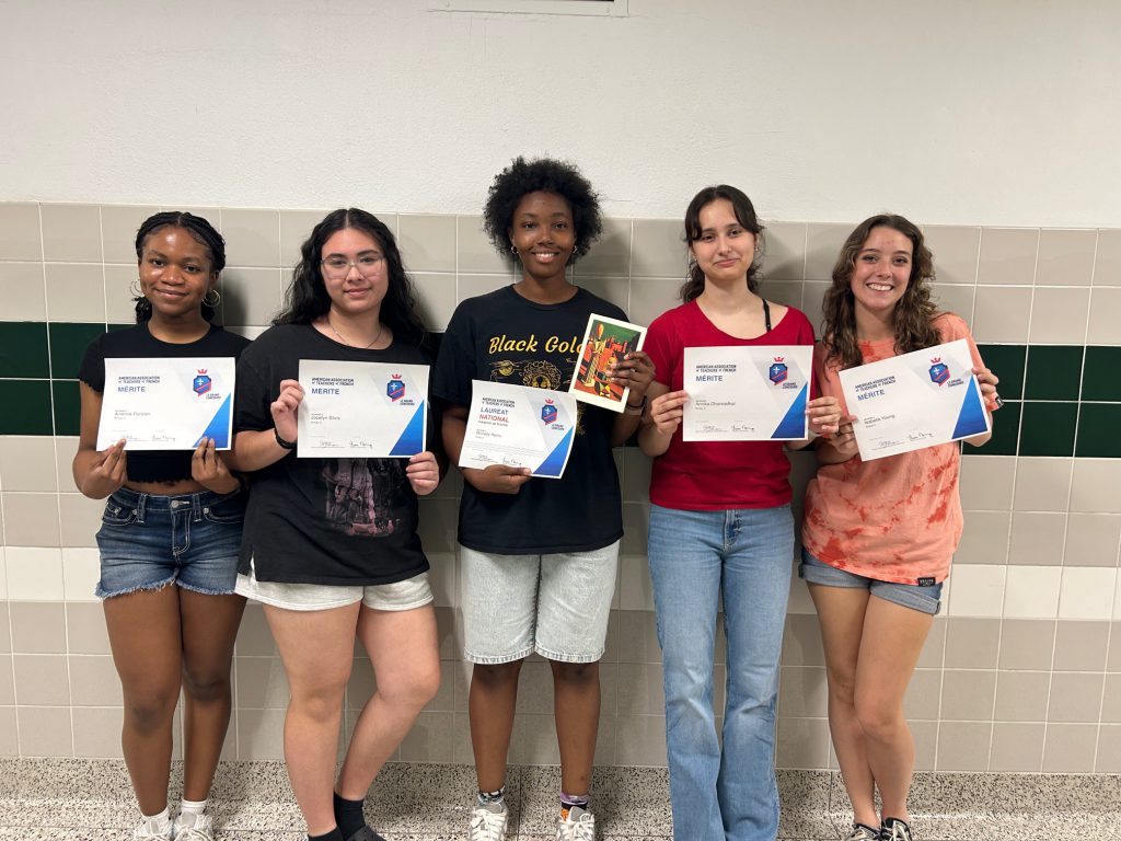 Students hold up certificates.