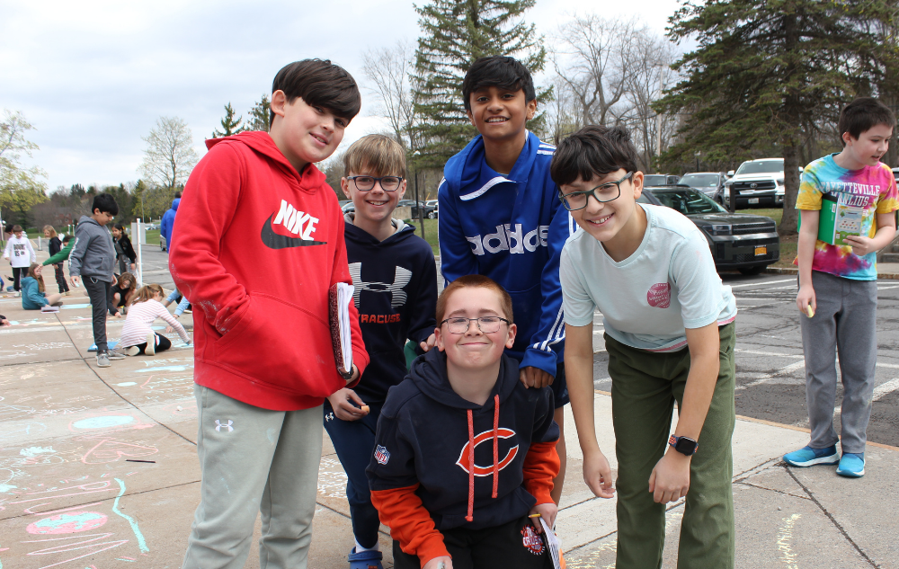 a group of students standing on a sidewalk holding chalk