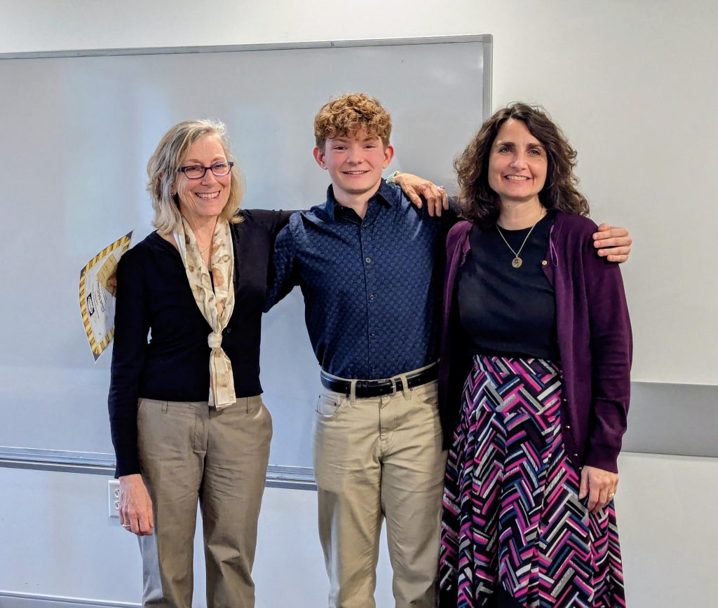 An FMHS student and two teachers smile.