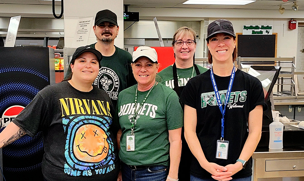 Five members of the Food Service team pose in a school kitchen.