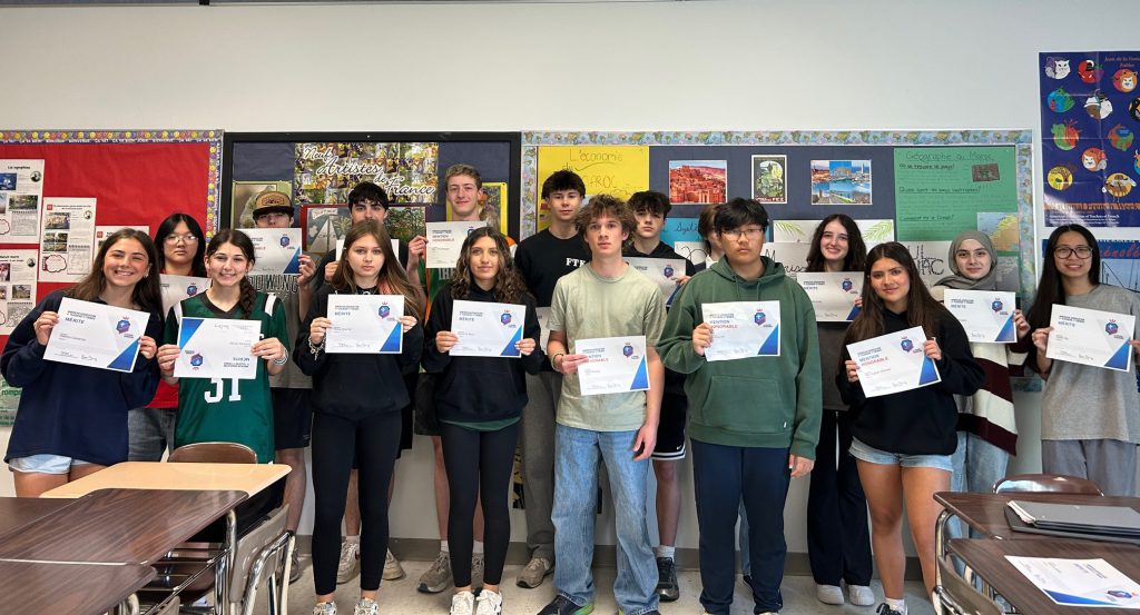 Students hold up certificates.