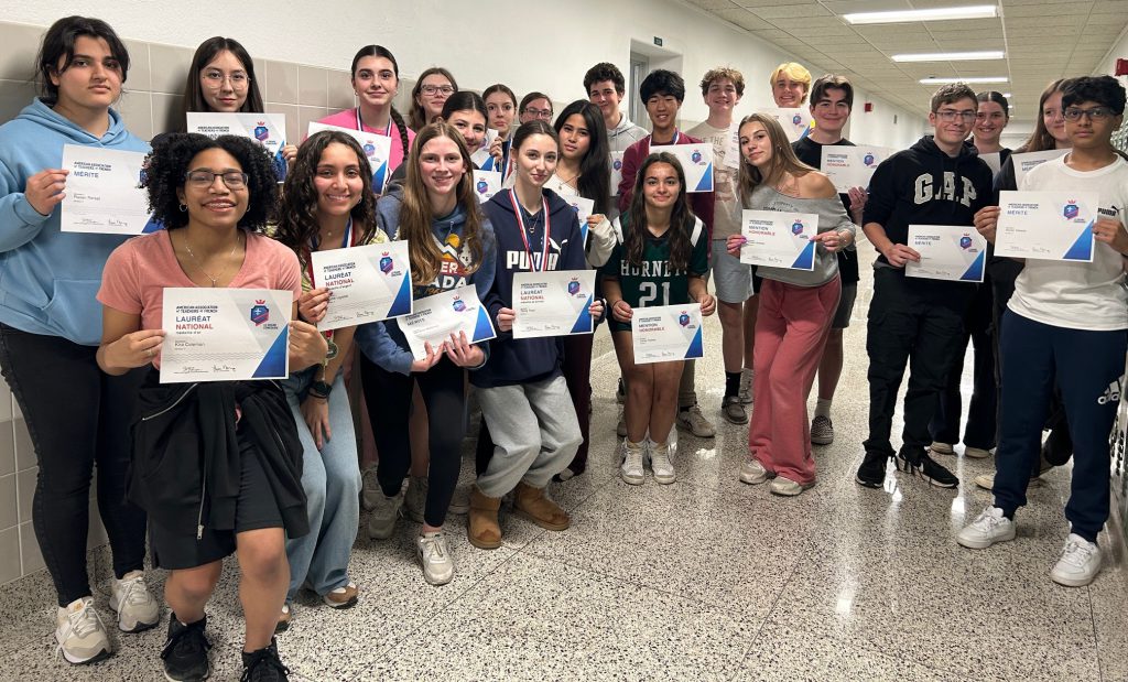 Students hold up certificates.