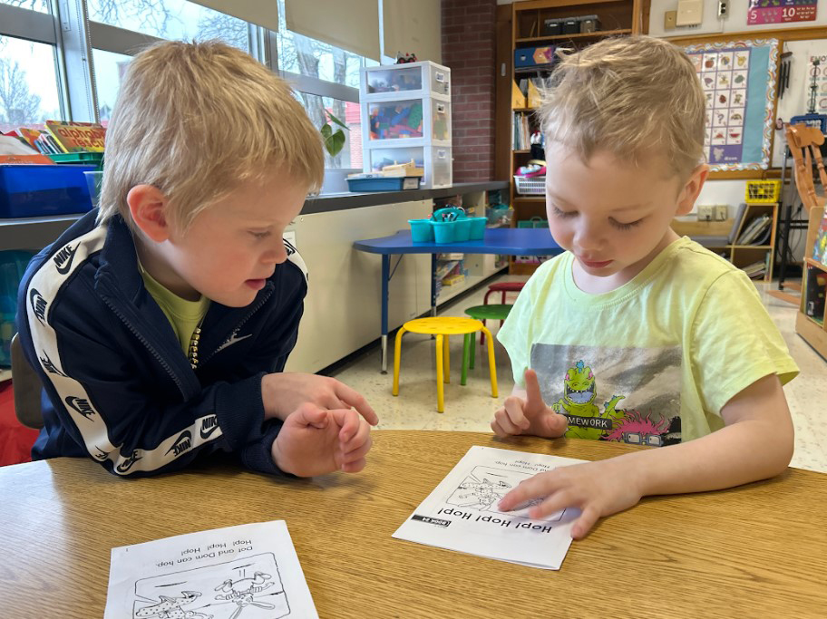 Two elementary aged children read a pamphlet titled "Help! Hop! Hop!"