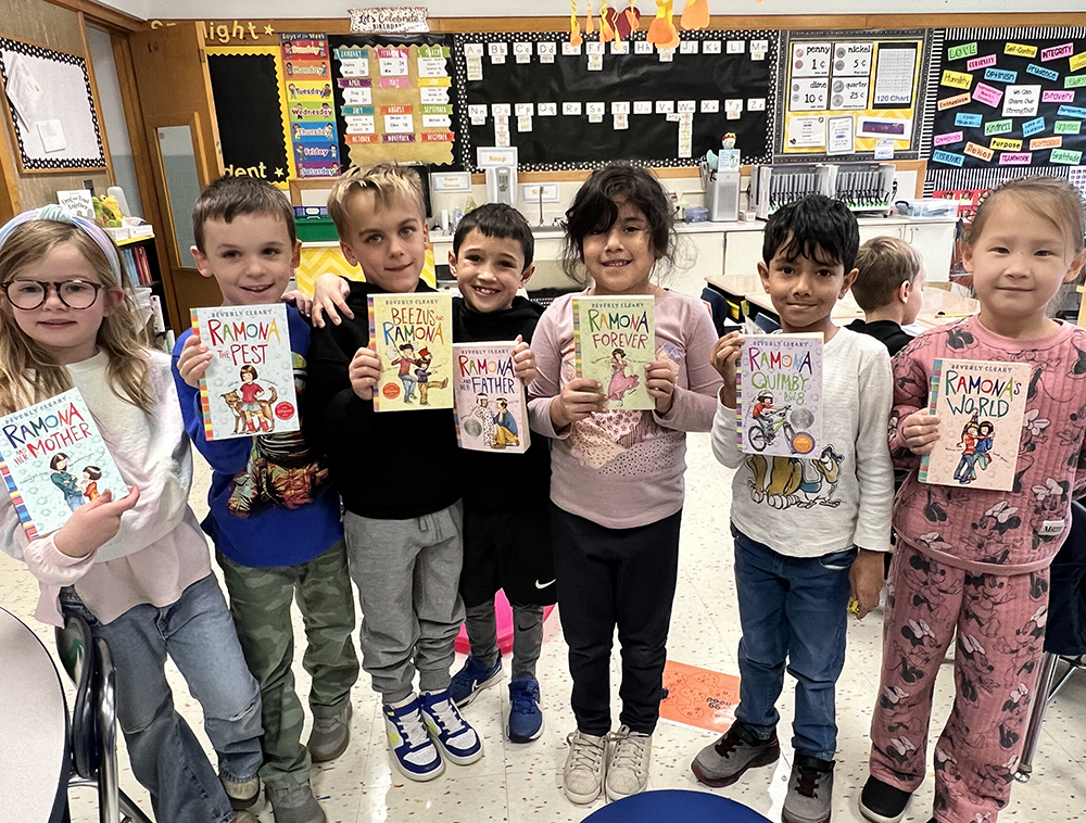 Several elementary students stand together holding various Ramona Quimby books.