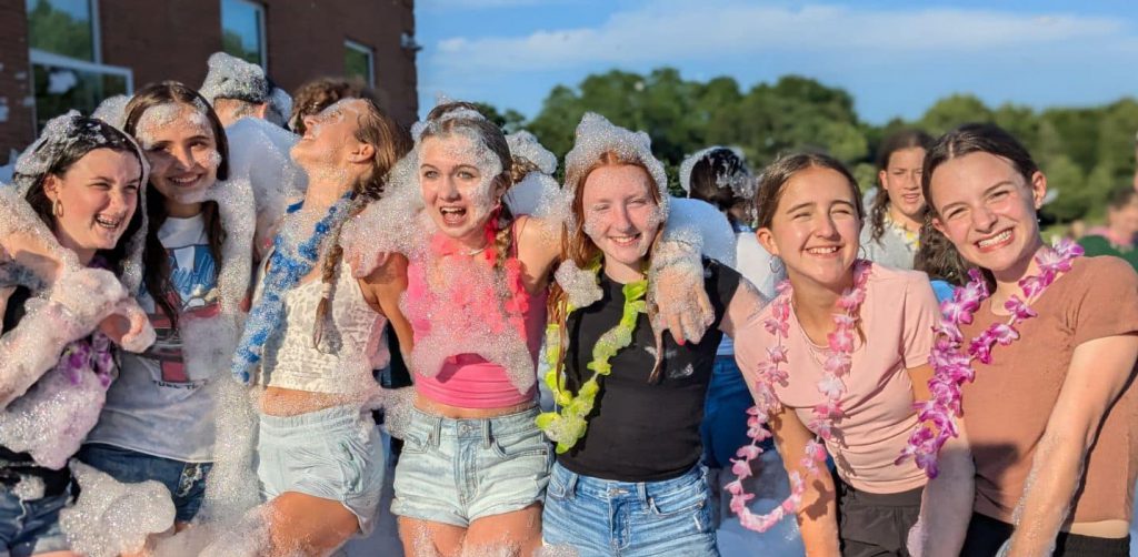 Several middle school students gather joyfully at an outdoor bubble party.
