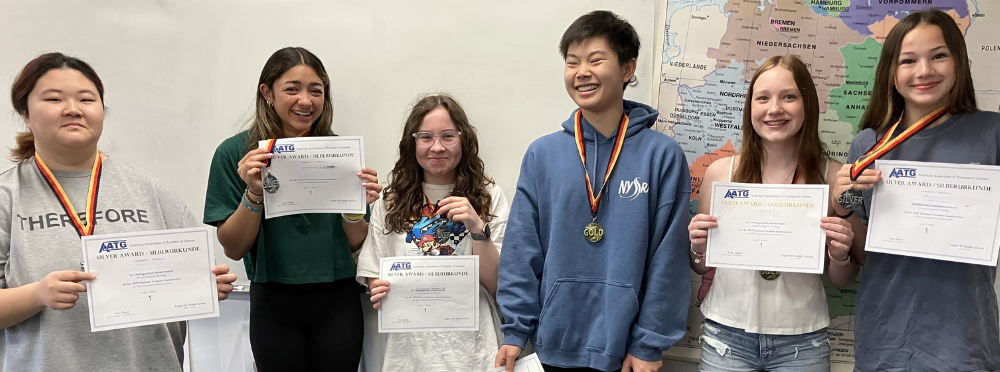 a group of students holding certificates and wearing medals around their necks