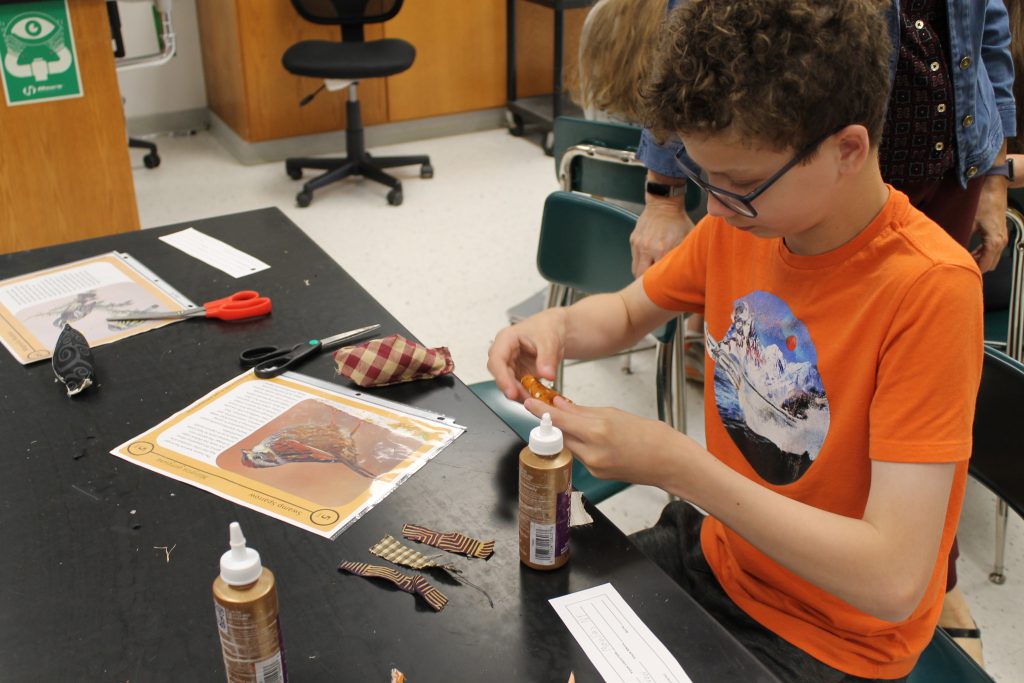 Student glues fabric onto art project.
