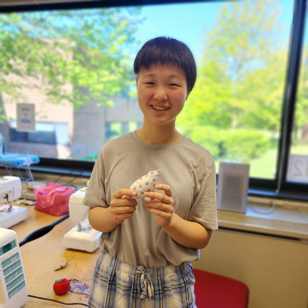 A student holds up a fabric bird.