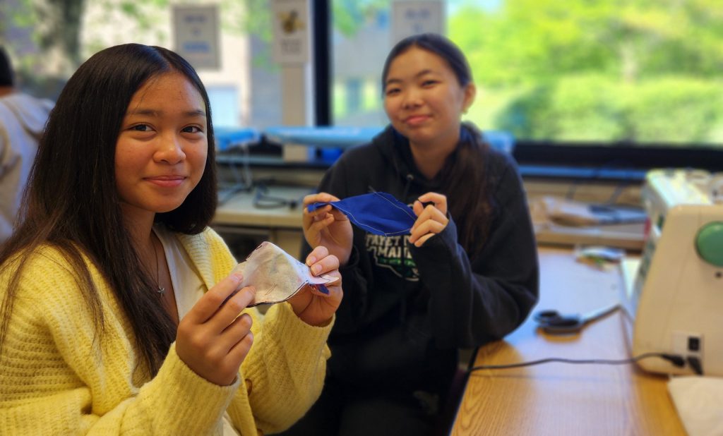 Two students proudly display cuts of cloth.