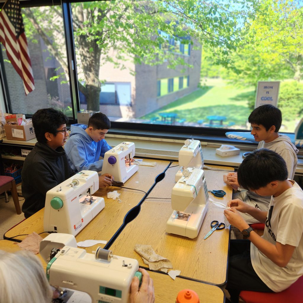 Students sew together at a table.