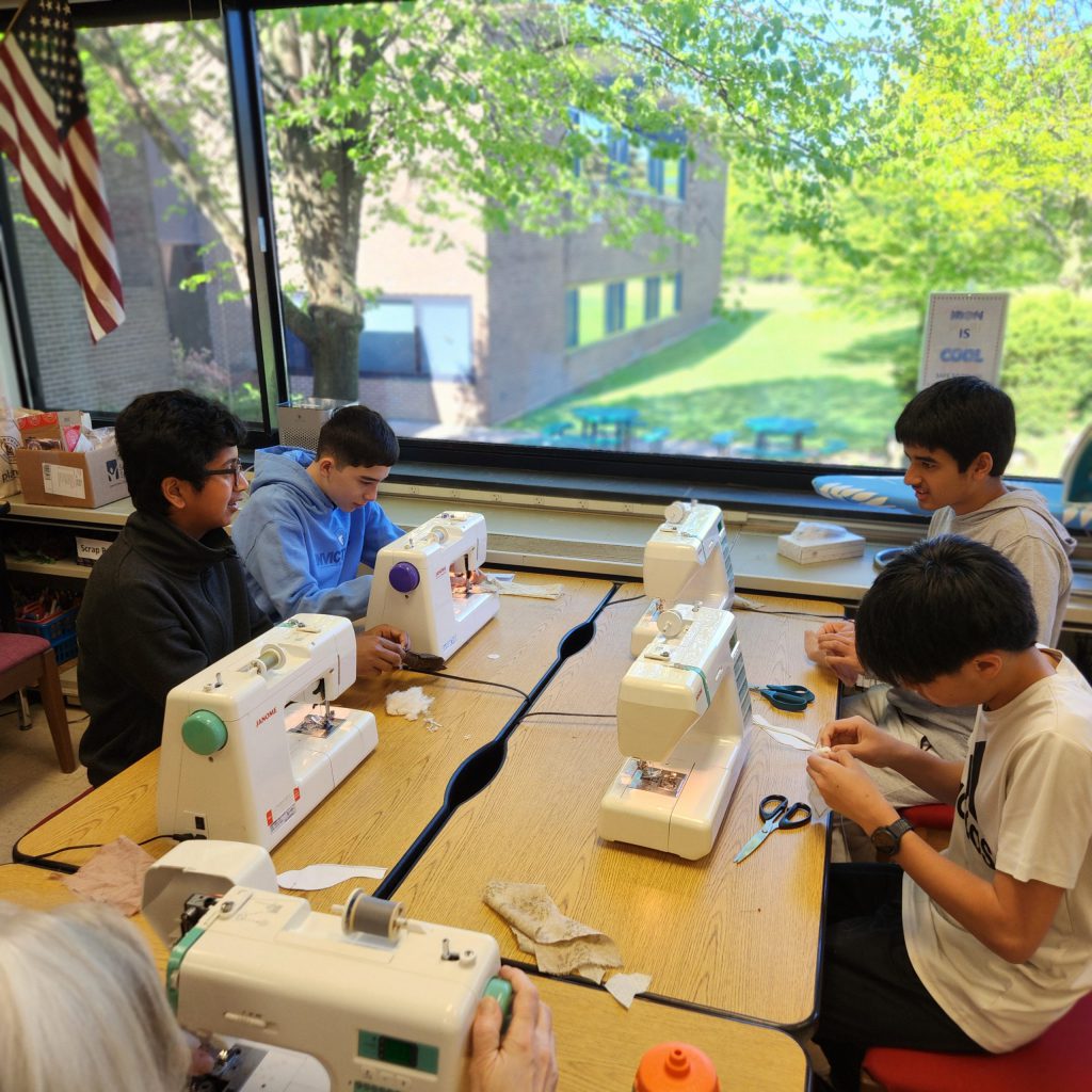 Four middle school students work at sewing machines.