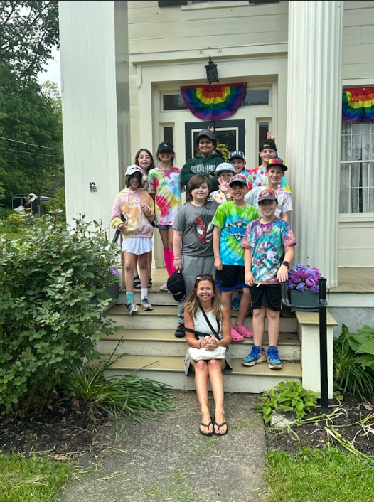 students and their teacher pose for a picture outside a building on their field trip