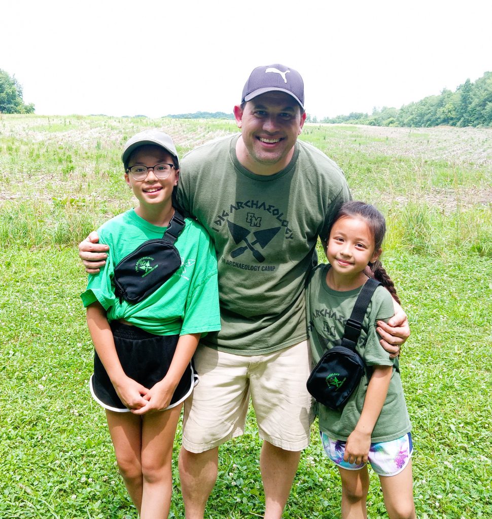 Camp teacher poses with two students.