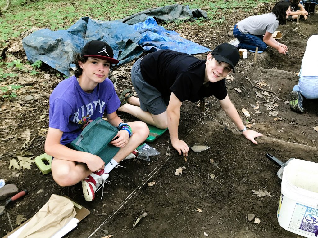 Students smile while digging for items.