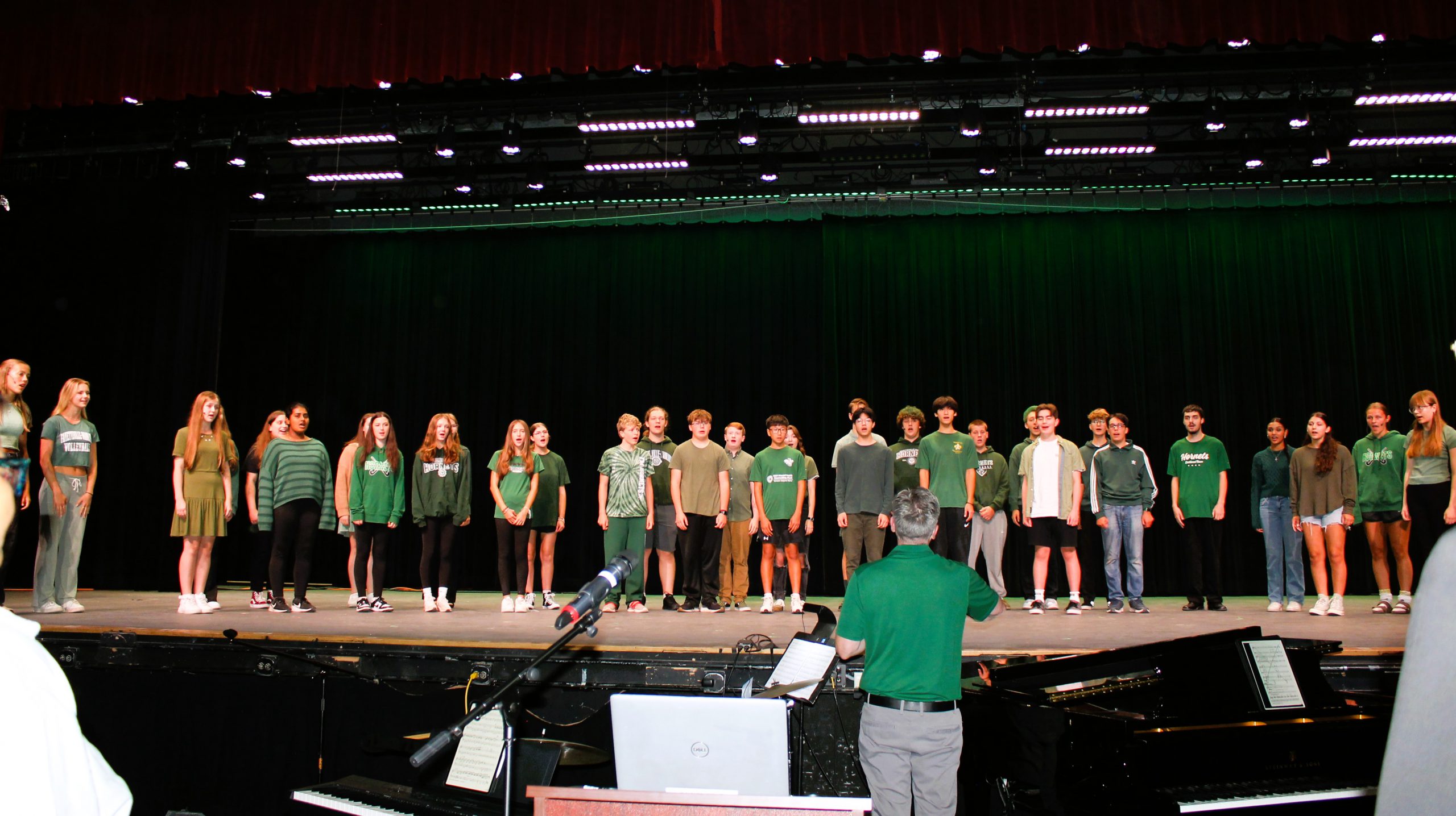 High school students perform on stage during staff meeting.