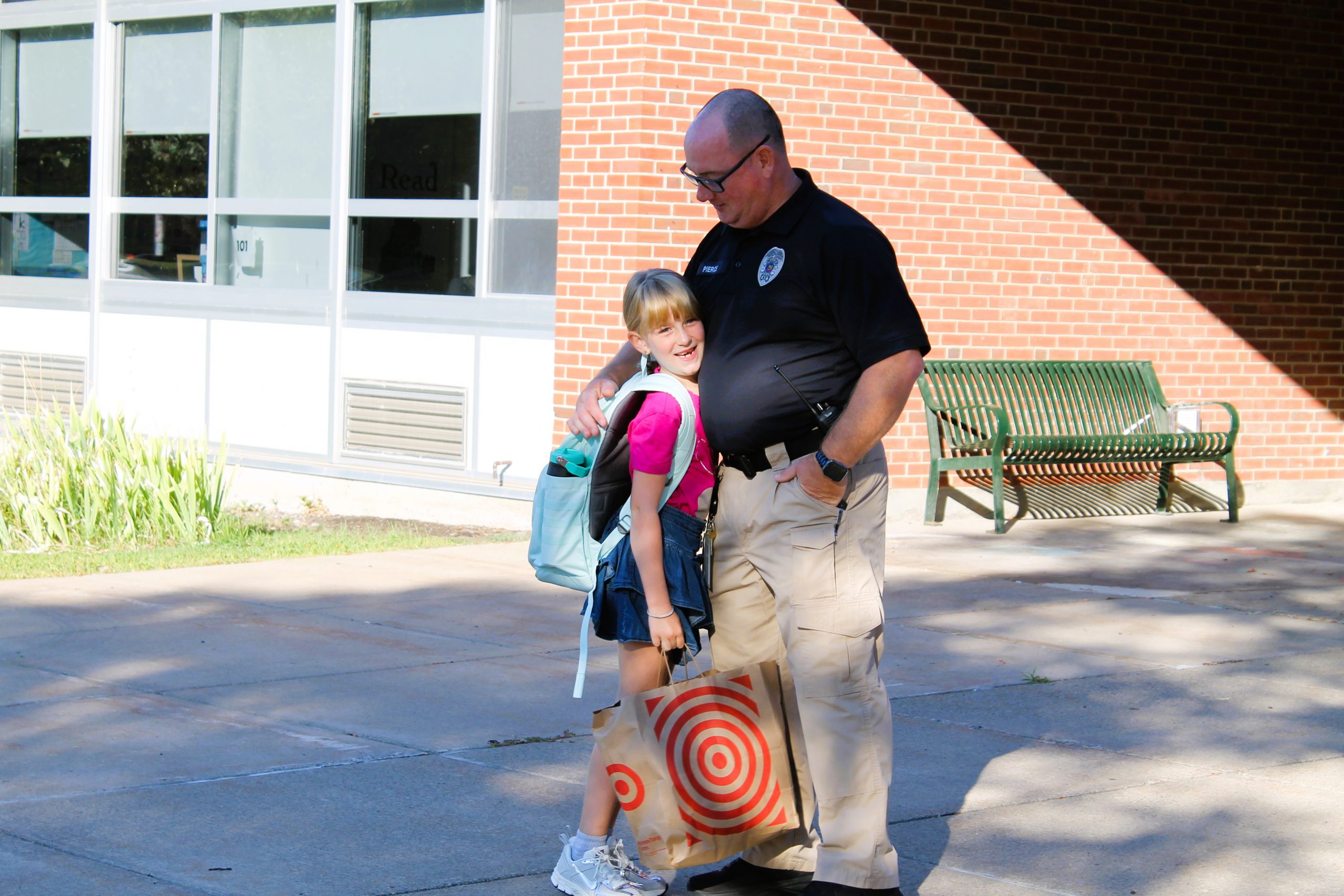 Student hugs school patrol officer in front of school.