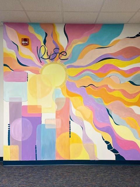 Colorful mural of a sun with rays with script that says rise.