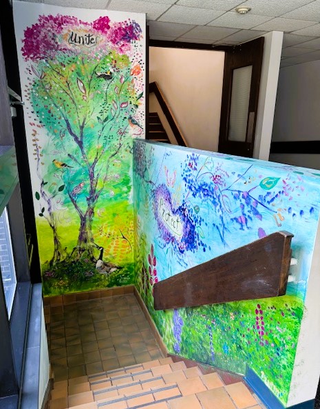 Whimsical painting of trees and wildlife in a stairwell.