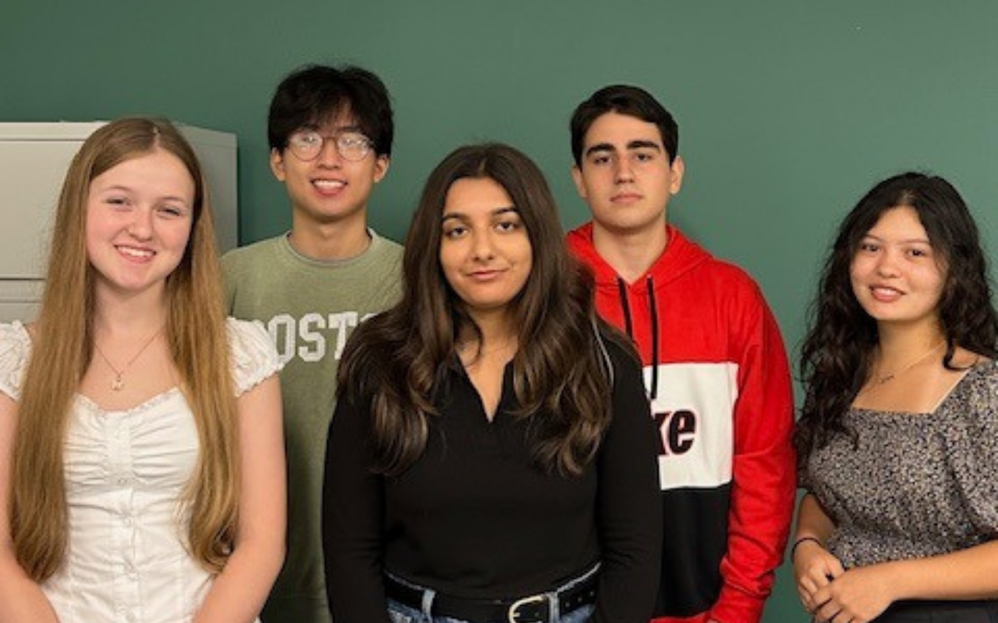 a group of students standing in front of a green wall