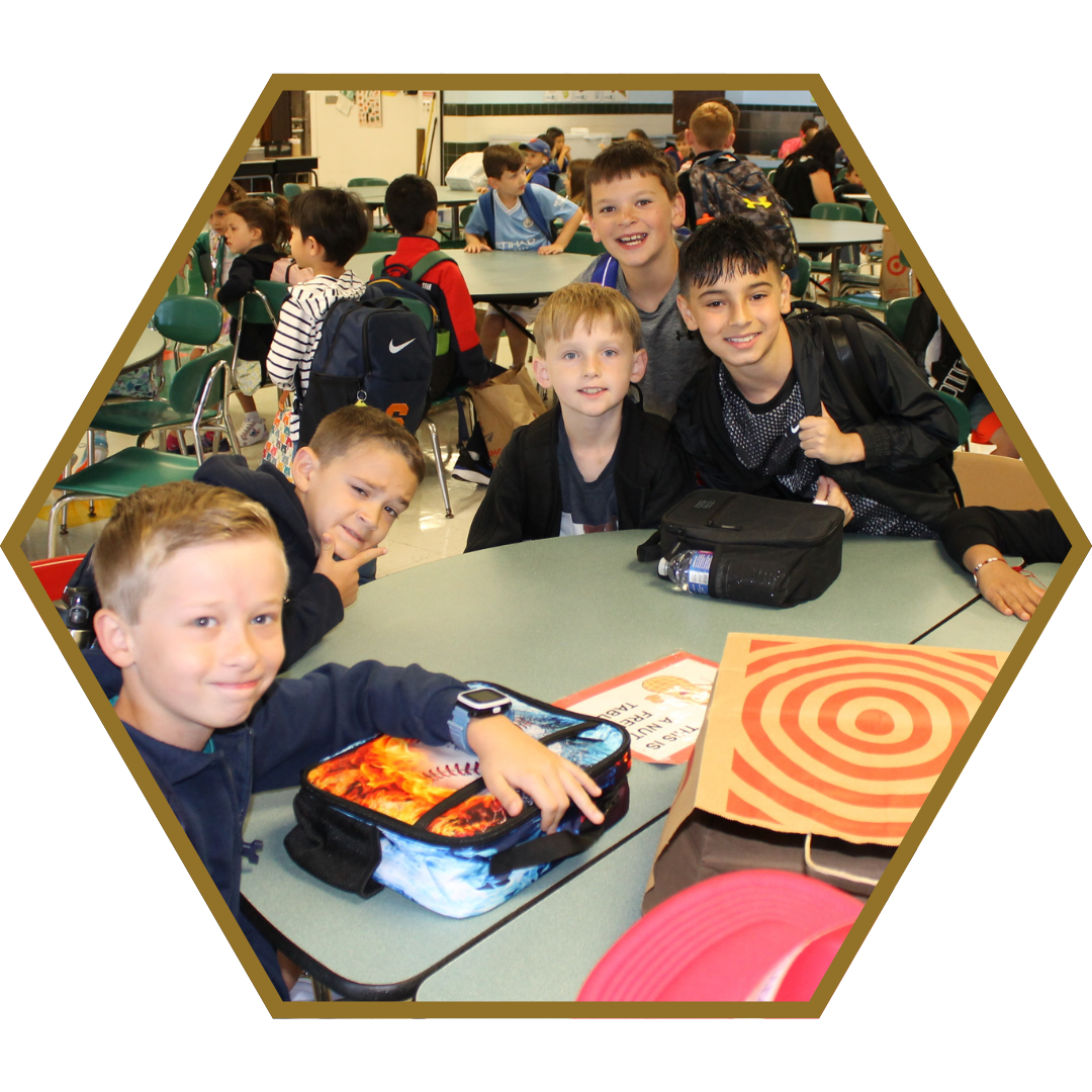 elementary students sitting at a table in the cafeteria with their lunch pails