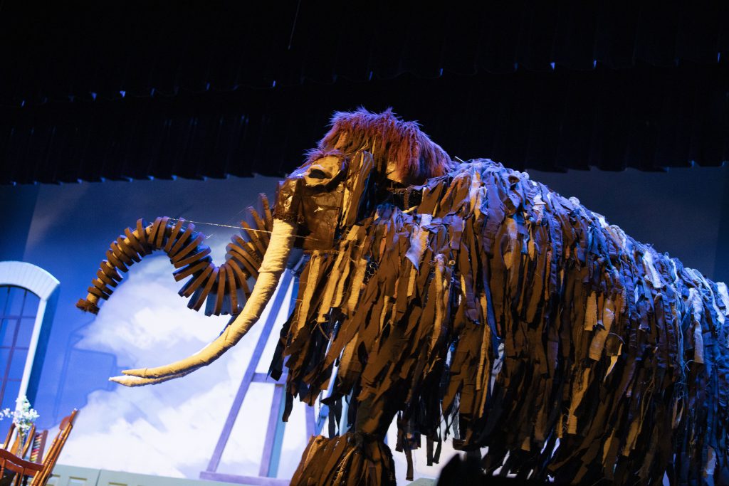 Mammoth puppet walks on stage during performance.