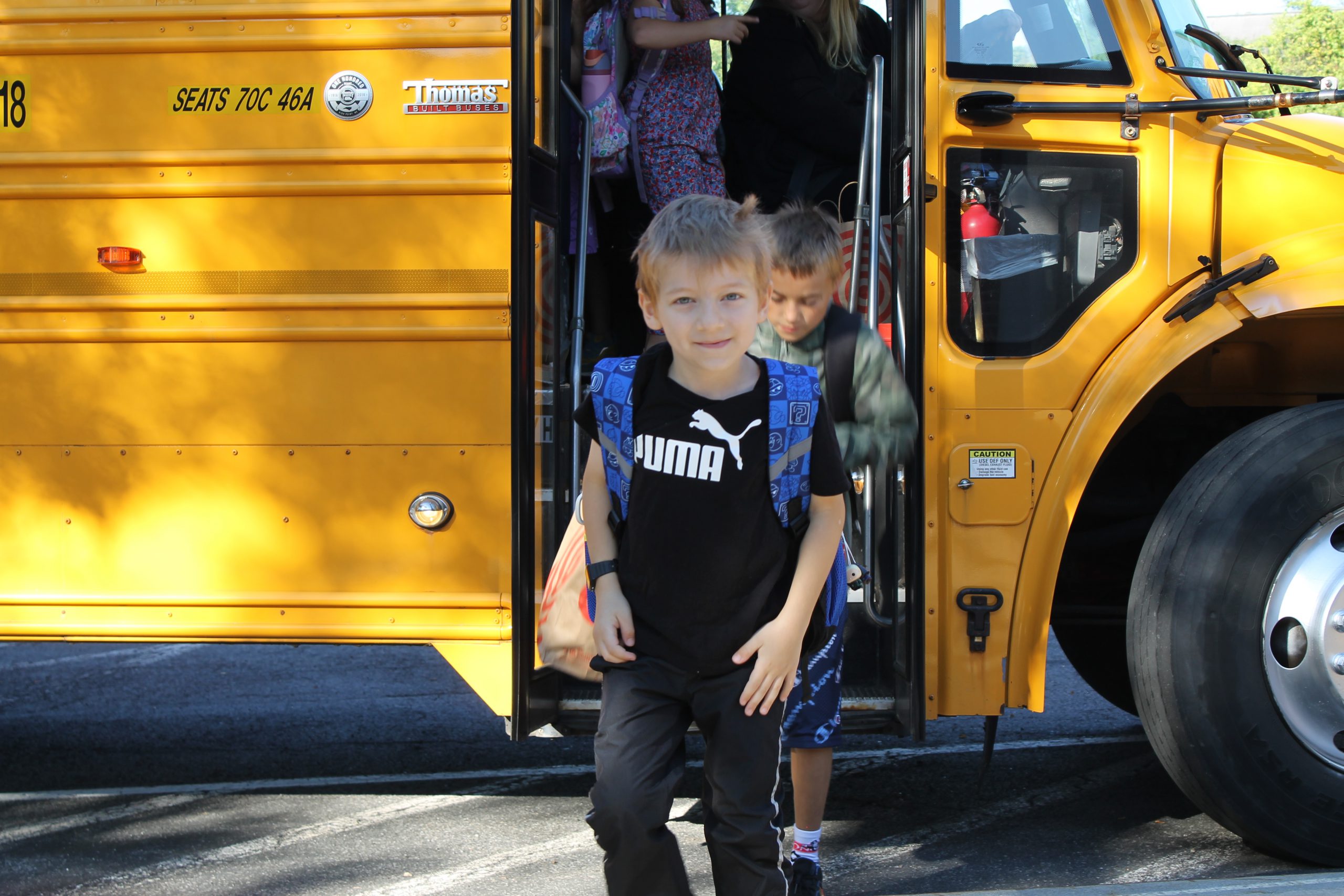 Boy getting off a school bus, looking at the camera