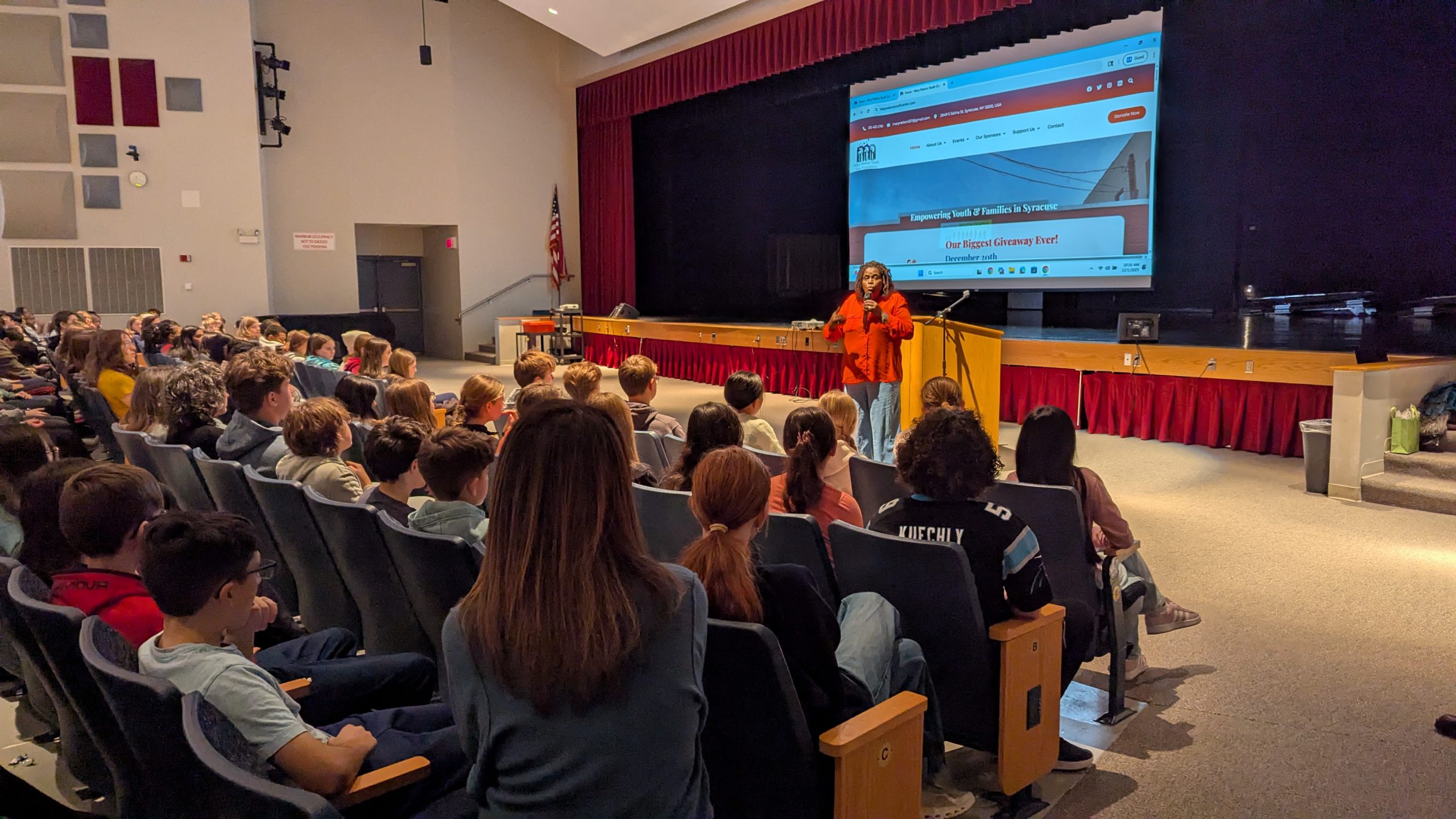 Mary Nelson speaks in front of Eagle Hill students in auditorium.