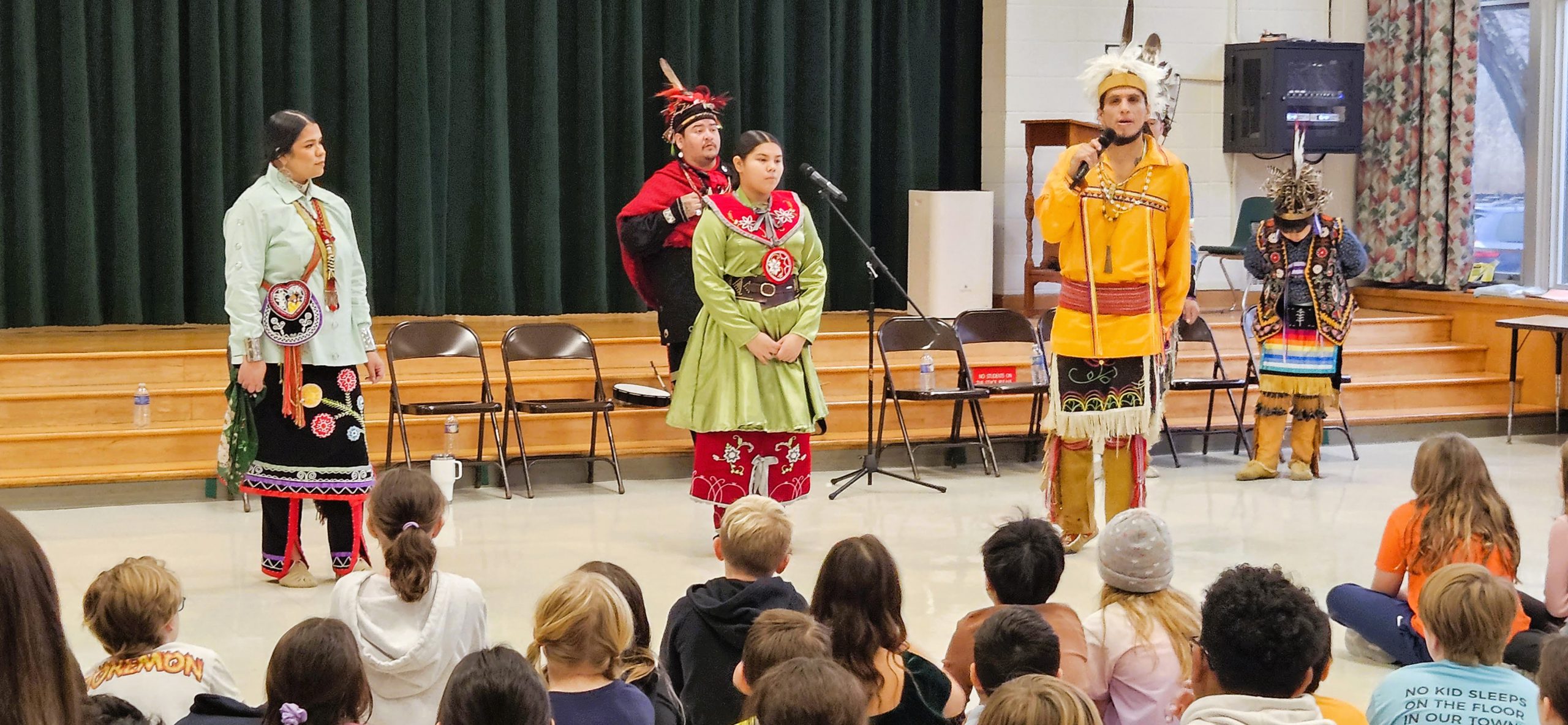 Haudenosaunee dancers and singers perform in front of students during assembly.