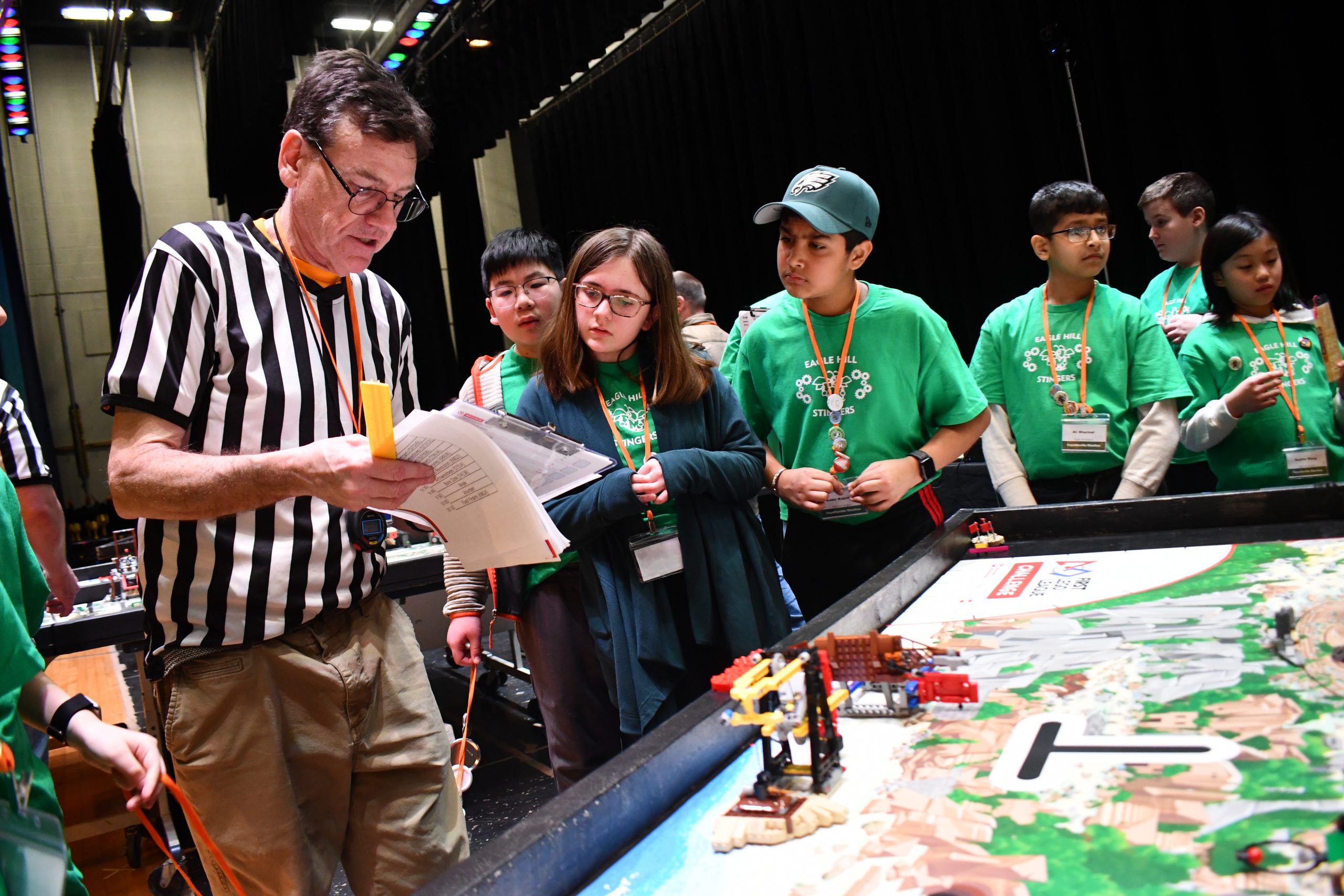 Eagle Hill students wear green t-shirts and check scores with judge during Lego stem contest.