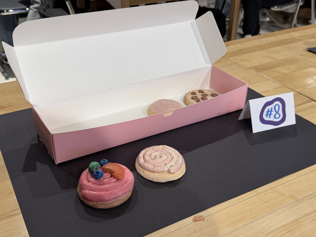 Pink Crumble Cookie box with sculptures of cookies in the box and on the table in front of the box