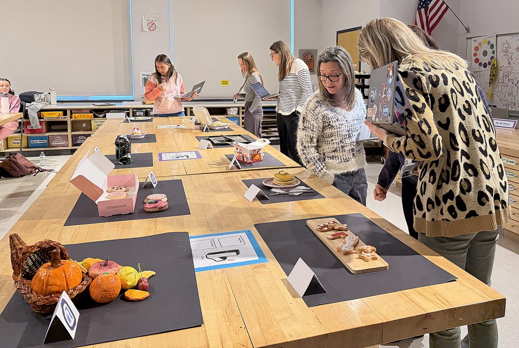 Judges are standing next to a table on which the sculptures are displayed; they are leaning over looking at the various displays