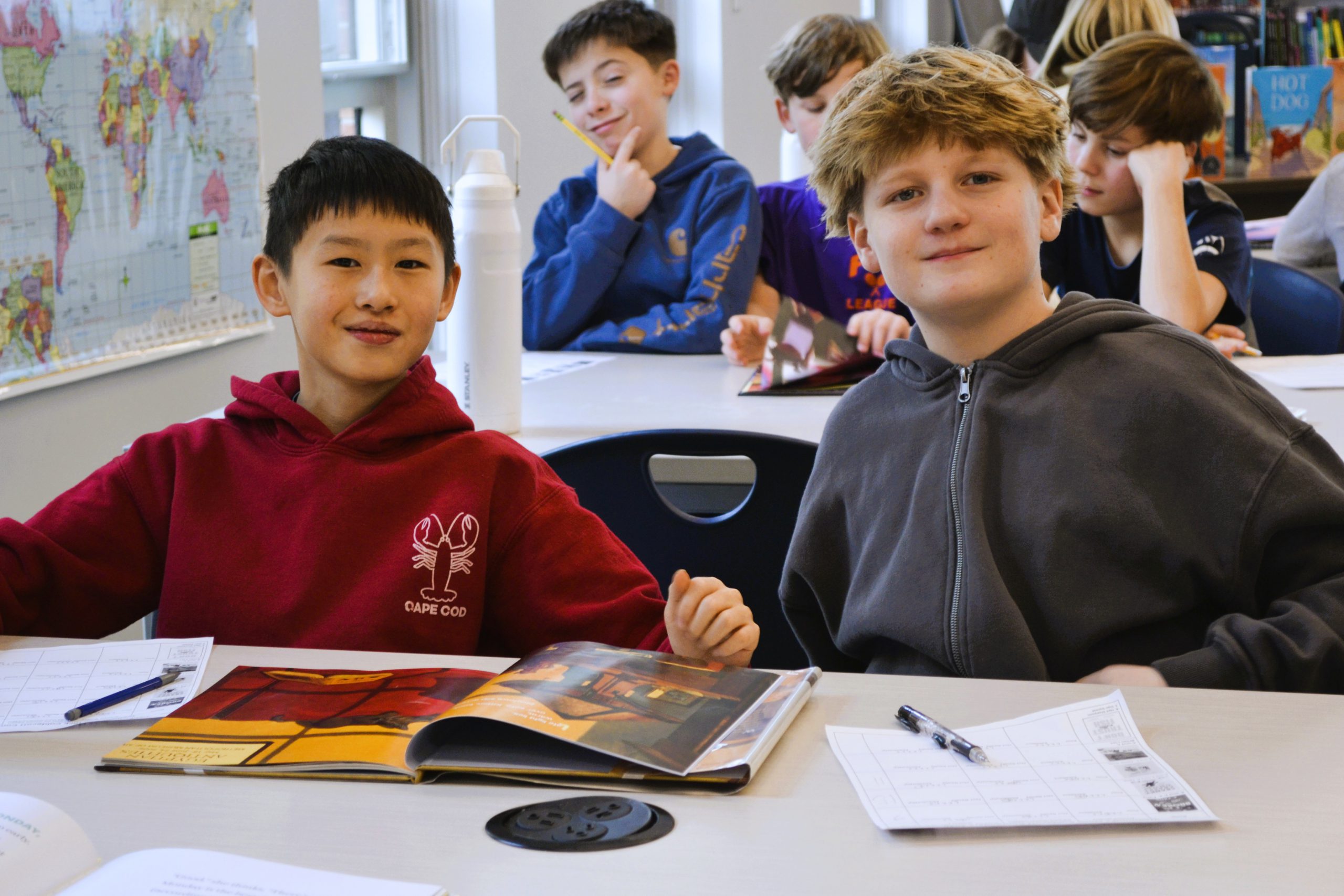 Students smile for camera while sitting at library desks.