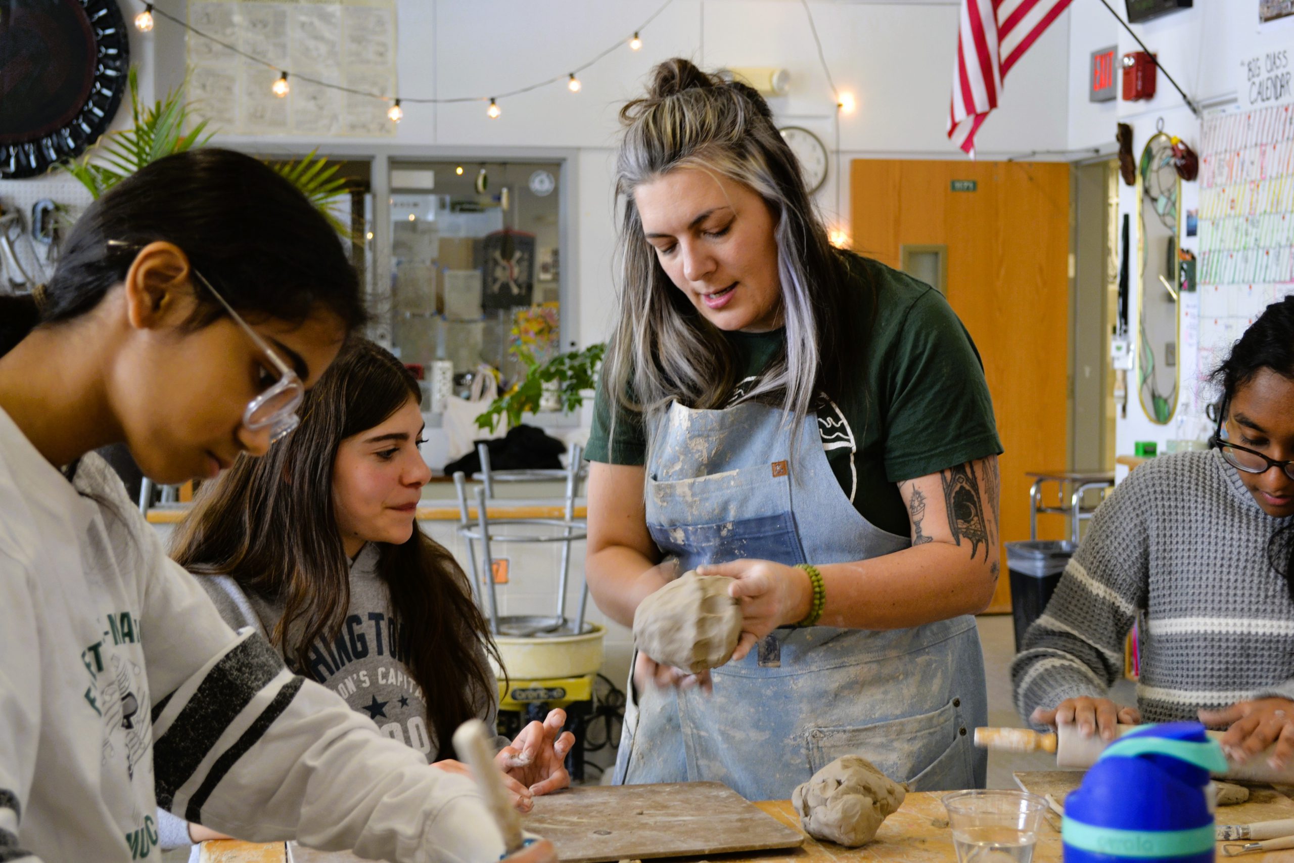 Art teacher shows student technique with clay.