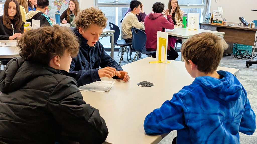 Middle school students sit at library tables during Battle of the Books session.
