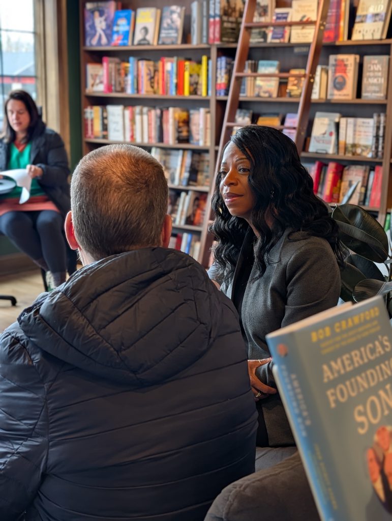 Dr. Parvey sits speaking with a man at meet and greet at book shop.