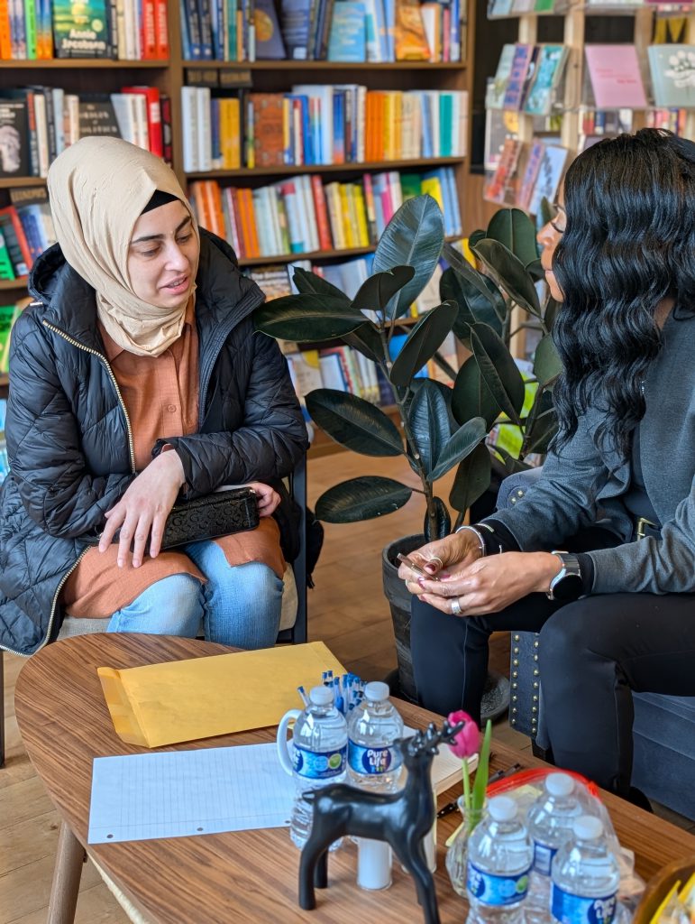 Dr. Parvey speaks with woman sitting down in local bookshop.