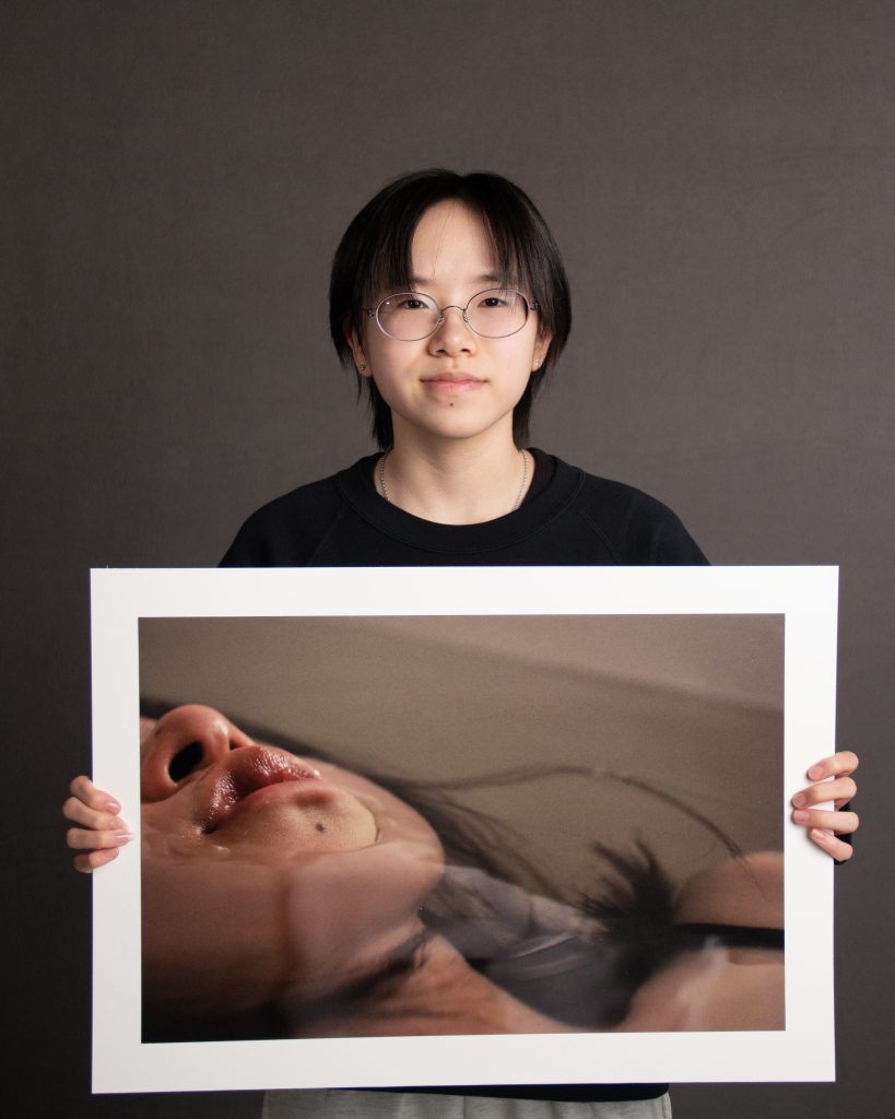 Student standing, holding large photo in front of body