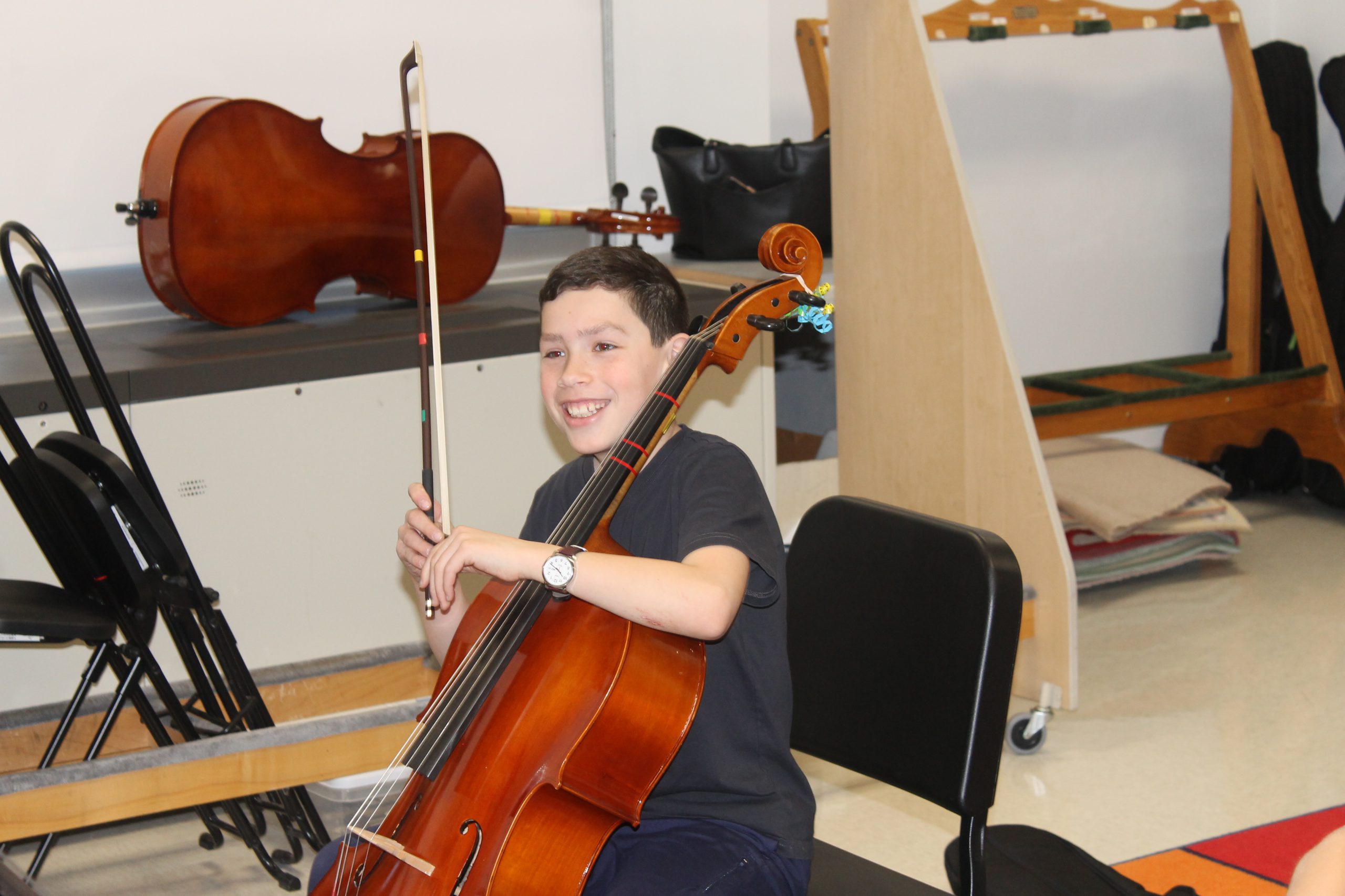 Student holding  cello and smiling