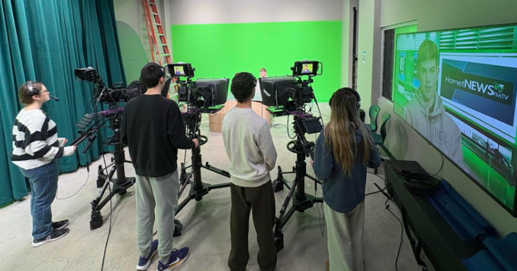 Students operate broadcast cameras with green screen in the background.
