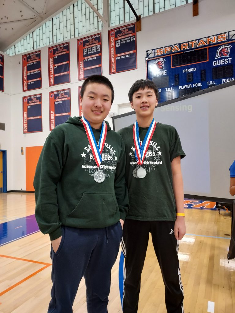 Two students standing side by side wearing medals