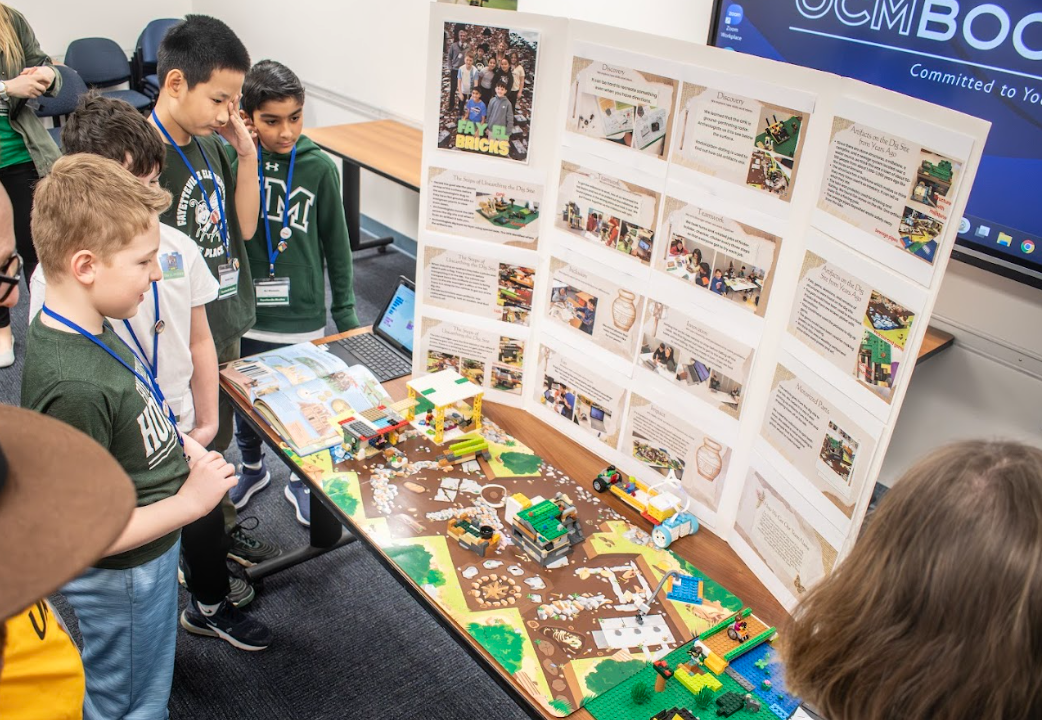 A group of elementary students stand in front of trifold display during science competition.