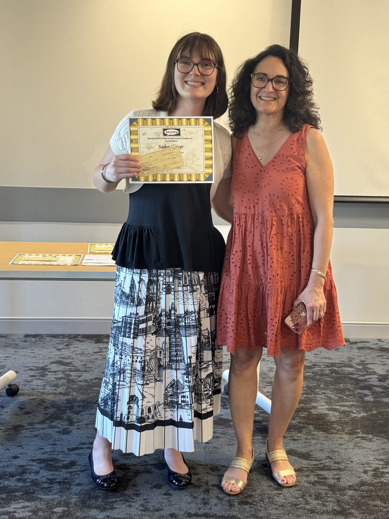Sadye Gitner poses for photo with teacher while holding certificate.