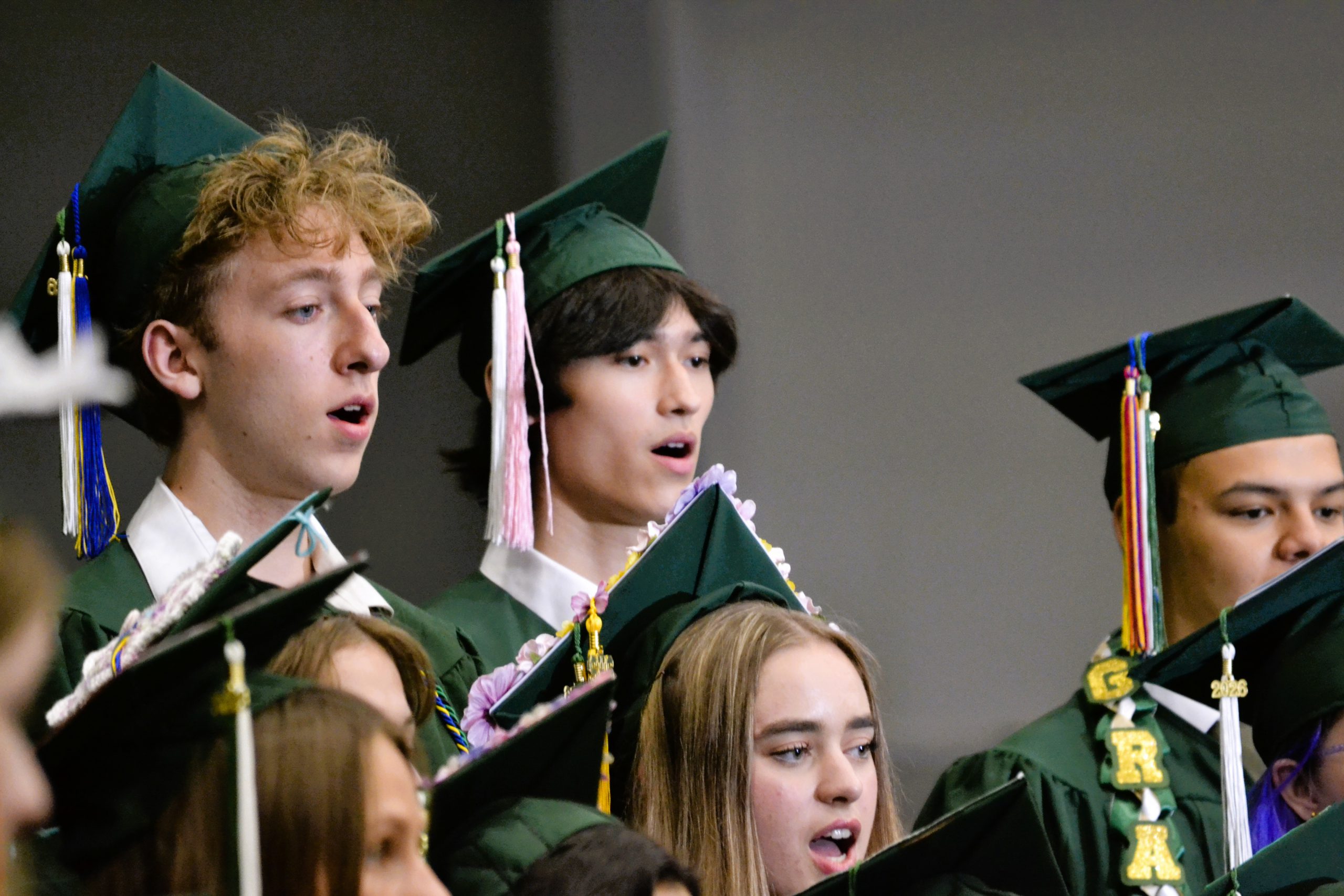 Seniors sing at graduation in caps and gowns.