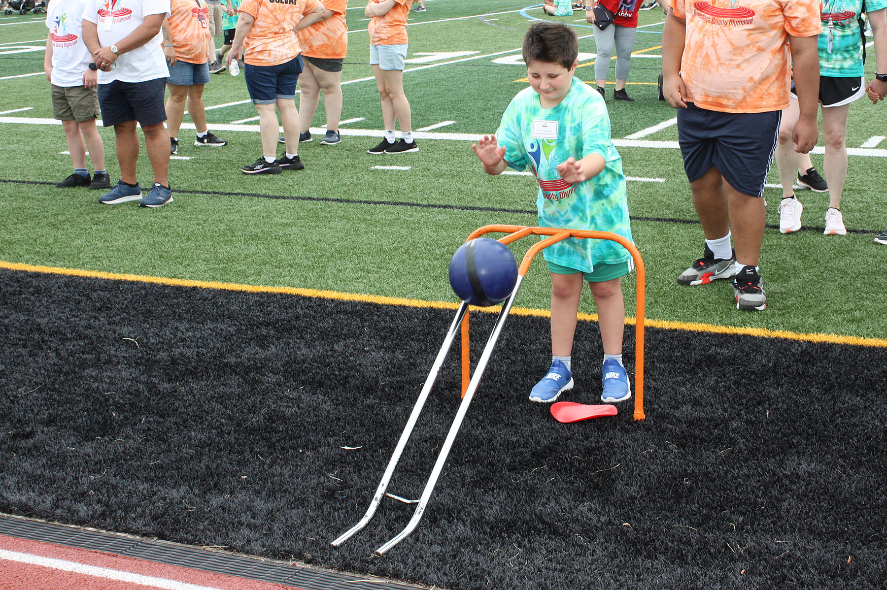 student rolling a bowling ball down a metal ramp